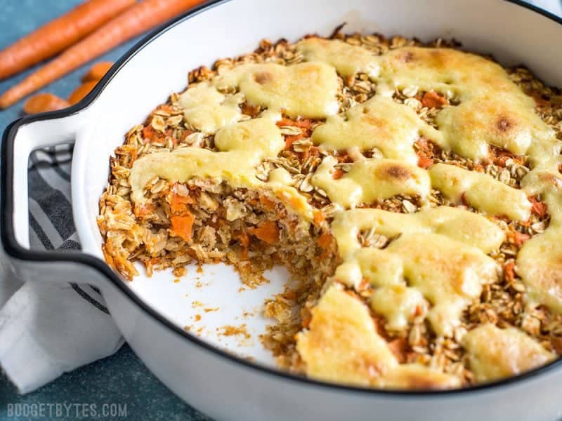 This Carrot Cake Baked Oatmeal is packed with healthy carrots and pops of sweetness from raisins and a cheesecake-inspired topping. Budgetbytes.com Carrot Cake Baked Oatmeal in casserole dish with some missing