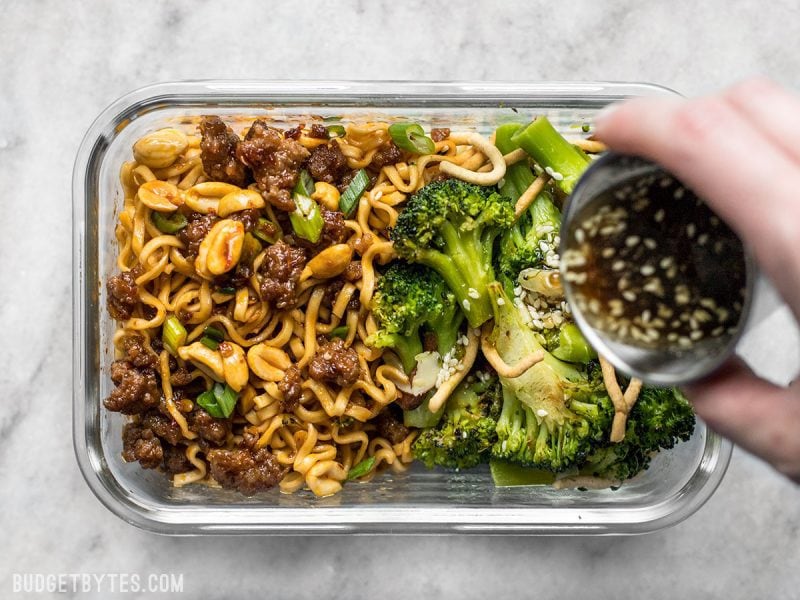 A little bit indulgent, a little bit healthy, this Pork and Peanut Dragon Noodle Meal Prep is a flavorful, filling, and DELICIOUS lunch! BudgetBytes.com Dressing being poured onto Broccoli Salad in the Pork and Peanut Dragon Noodle Meal Prep