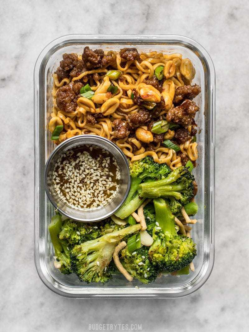 A little bit indulgent, a little bit healthy, this Pork and Peanut Dragon Noodle Meal Prep is a flavorful, filling, and DELICIOUS lunch! BudgetBytes.com A glass meal prep container with Pork and Peanut Dragon Noodles and Broccoli Salad