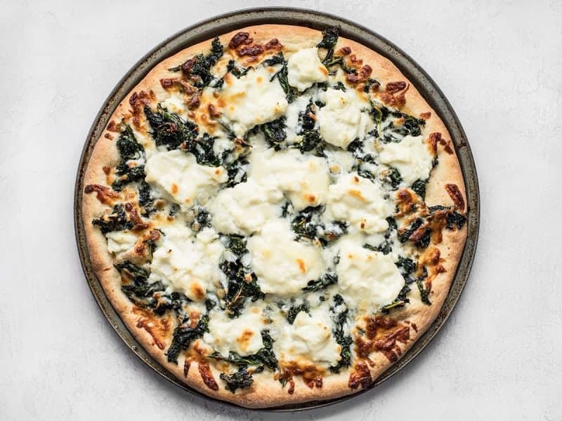 Garlicky greens and creamy ricotta pair perfectly on this light and fresh Garlicky Kale and Ricotta Pizza. It’s the perfect pizza for summer! BudgetBytes.com Finished Garlicky Kale and Ricotta Pizza