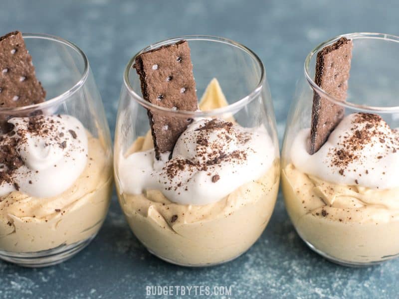 Peanut Butter Fluff Cups are the easiest and most decadent dessert you’ve ever made. They come together in minutes with no baking required! BudgetBytes.com Three Peanut Butter Fluff Cups lined up in a row