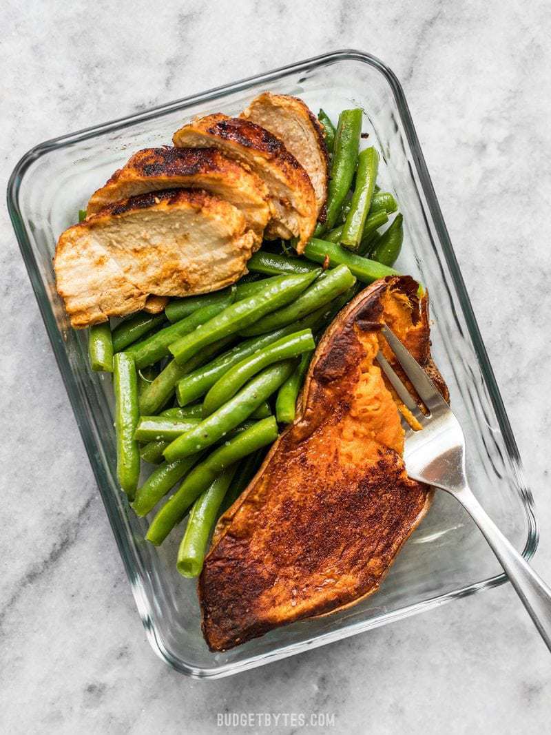 Smoky Chicken and Cinnamon Roasted Sweet Potato Meal Prep is an easy, delicious, filling, and healthy daily lunch or dinner. BudgetBytes.com One meal prep container with Smoky Chicken and Cinnamon Roasted Sweet Potatoes and a fork