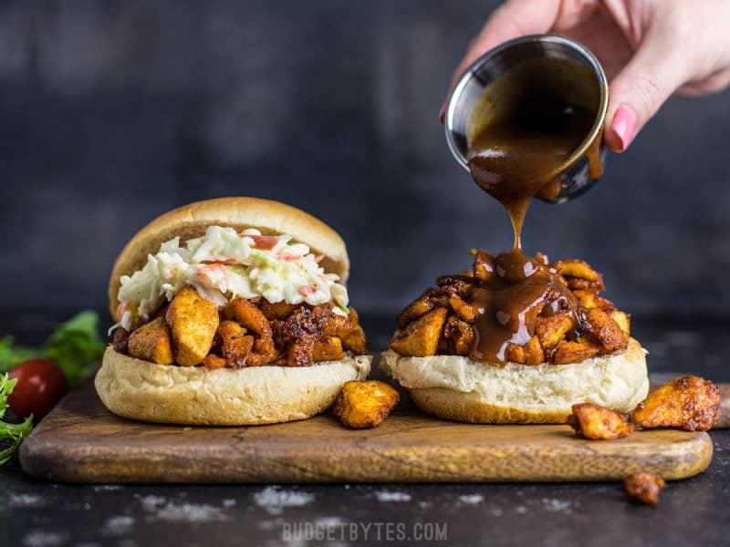 BBQ Tofu Sliders are an easy and inexpensive alternative to pulled meat sandwiches. With a simple ingredient list, this is a tofu dish anyone can master! Front view of BBQ sauce being drizzled onto an open BBQ Tofu Slider.