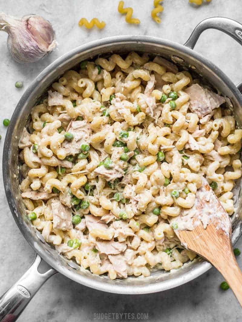 This quick and comforting Creamy Tuna Pasta with Peas and Parmesan is a fast and easy weeknight dinner that only requires a few simple ingredients. Budgetbytes.com A large skillet full of Creamy Tuna Pasta with Peas and Parmesan with a wooden spatula
