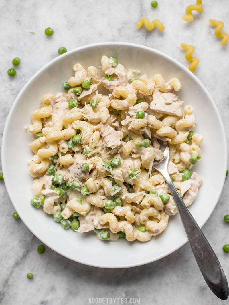 This quick and comforting Creamy Tuna Pasta with Peas and Parmesan is a fast and easy weeknight dinner that only requires a few simple ingredients. Budgetbytes.com A white bowl of Creamy Tuna Pasta with Peas and Parmesan with a fork