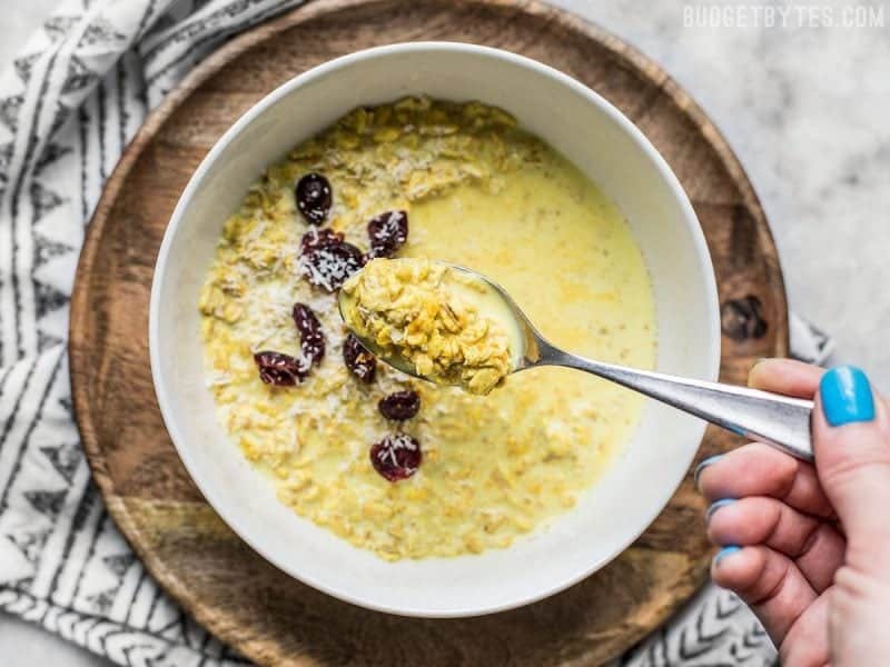 Earthy, slightly sweet, and full of aromatic spices, these Golden Milk Overnight Oats will be your new favorite make ahead summer breakfast! A spoonful of Golden Overnight Oats being lifted from the bowl.