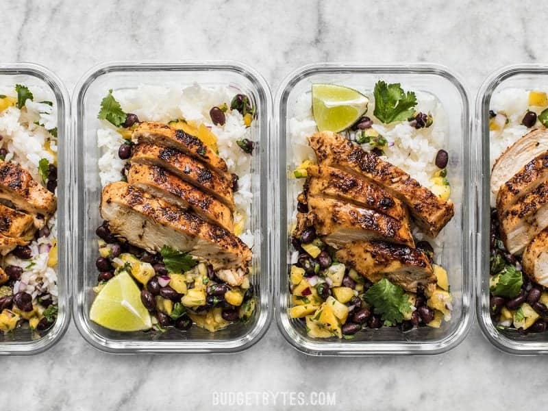 Full of fresh summery flavor, with just a few ingredients, this Jerk Chicken with Pineapple Black Bean Salsa will become your new go-to easy summer meal! Glass meal prep containers with Jerk Chicken and Pineapple Black Bean Salsa lined up in a row.