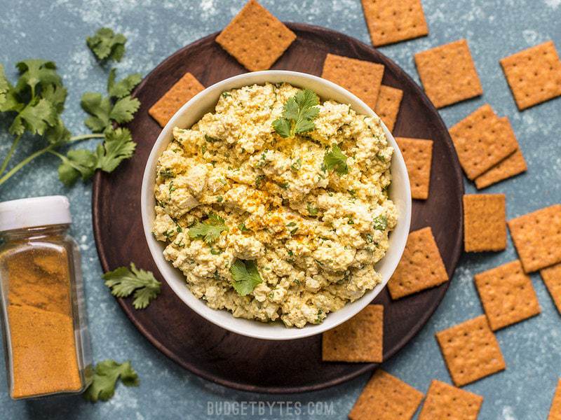 This cold, refreshing, and highly flavored Curried Tofu Salad is the perfect quick fix for summer or cold-pack lunch. Budgetbytes.com A bowl of Curried Tofu Salad surrounded by crackers
