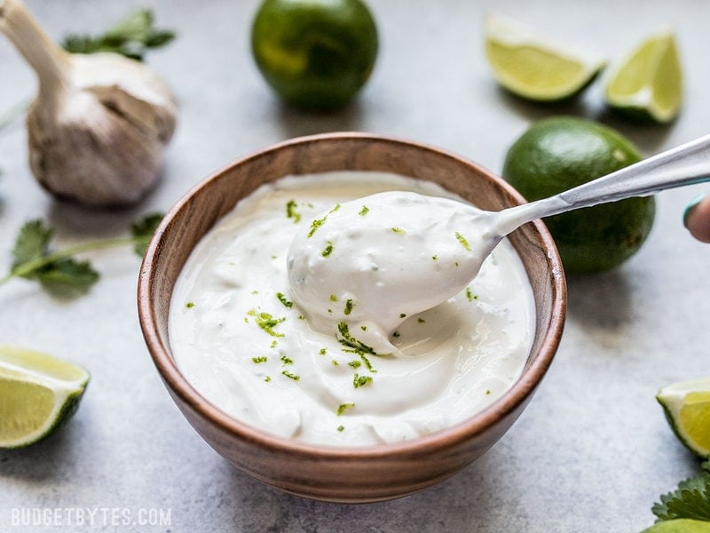 This tangy, creamy, fresh, and garlicky Lime Crema is the key to taking your tacos, nachos, salads, and more to the next level. Budgetbytes.com A spoon scooping Lime Crema out of a small bowl