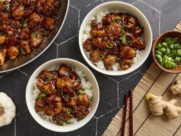 Overhead view of sesame chicken in bowls with rice.