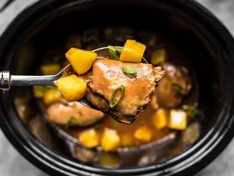 With just a few ingredients, dinner doesn’t get easier (or tastier) than this Slow Cooker Pineapple Teriyaki Chicken. Skip the take out tonight! Close up of a large spoonful of Slow Cooker Pineapple Teriyaki Chicken being pulled from the slow cooker.