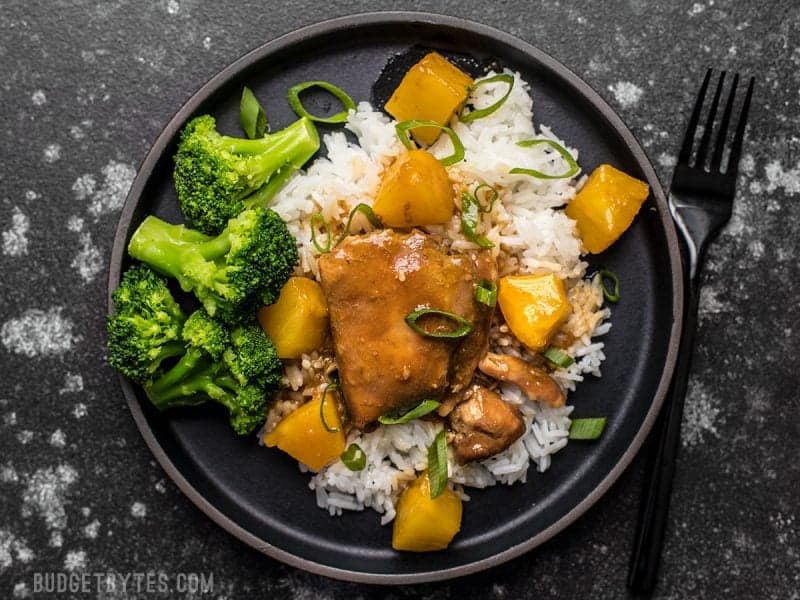 With just a few ingredients, dinner doesn’t get easier (or tastier) than this Slow Cooker Pineapple Teriyaki Chicken. Skip the take out tonight! Slow Cooker Pineapple Teriyaki Chicken on a black stoneware plate with rice and broccoli