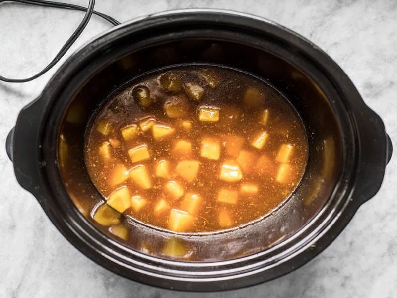 Thickened pineapple teriyaki chicken sauce with pineapple chunks in slow cooker