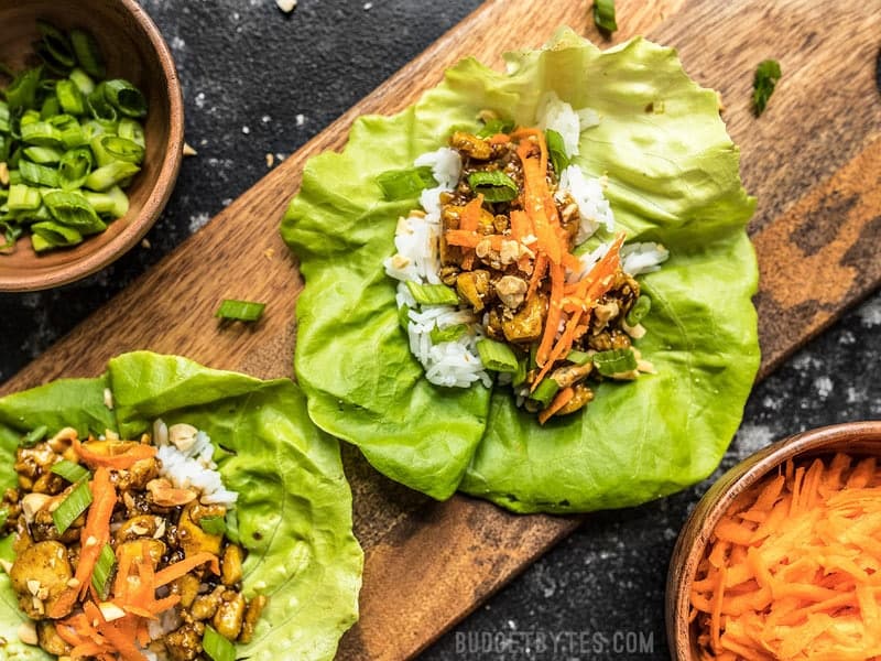 Skip the meat and make these light and fresh Hoisin Tofu Lettuce Cups, for a fast and easy weeknight dinner. Budgetbytes.com Close up of Hoisin Tofu Lettuce Cups arranged on a wooden cutting board