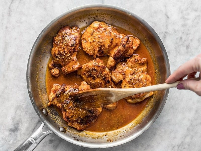 This sweet and tangy 20 Minute Honey Mustard Chicken will be your new family favorite weeknight dinner. Only a few pantry staples needed! Budgetbytes.com Honey mustard pan sauce being drizzled over chicken thighs in the skillet