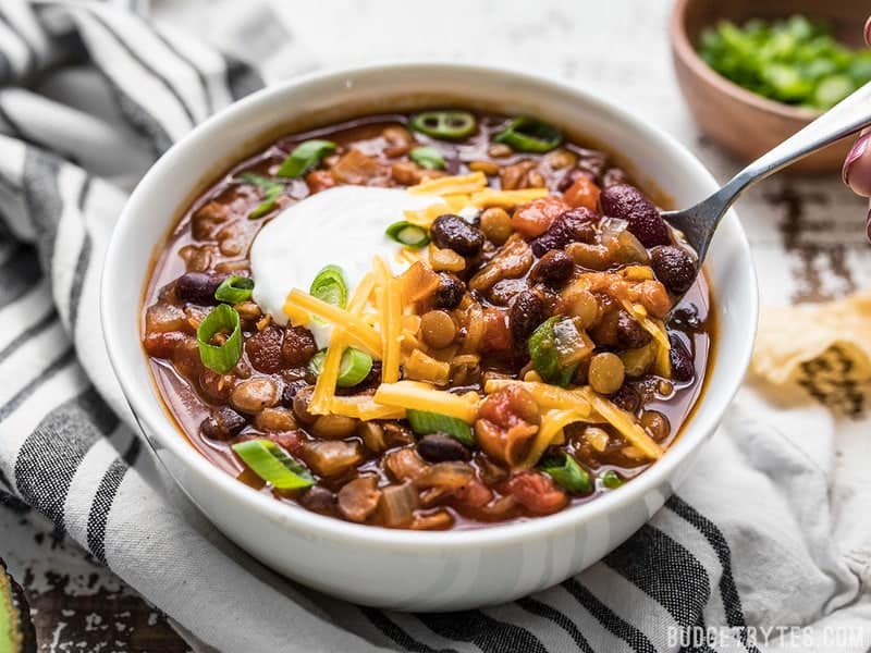 This Slow Cooker Vegetarian Lentil Chili makes a huge batch, is packed with flavor and nutrients, and can be made for only about 5 dollars! Budgetbytes.com Front view of a bowl of Slow Cooker Vegetarian Lentil Chili with cheese and sour cream on top