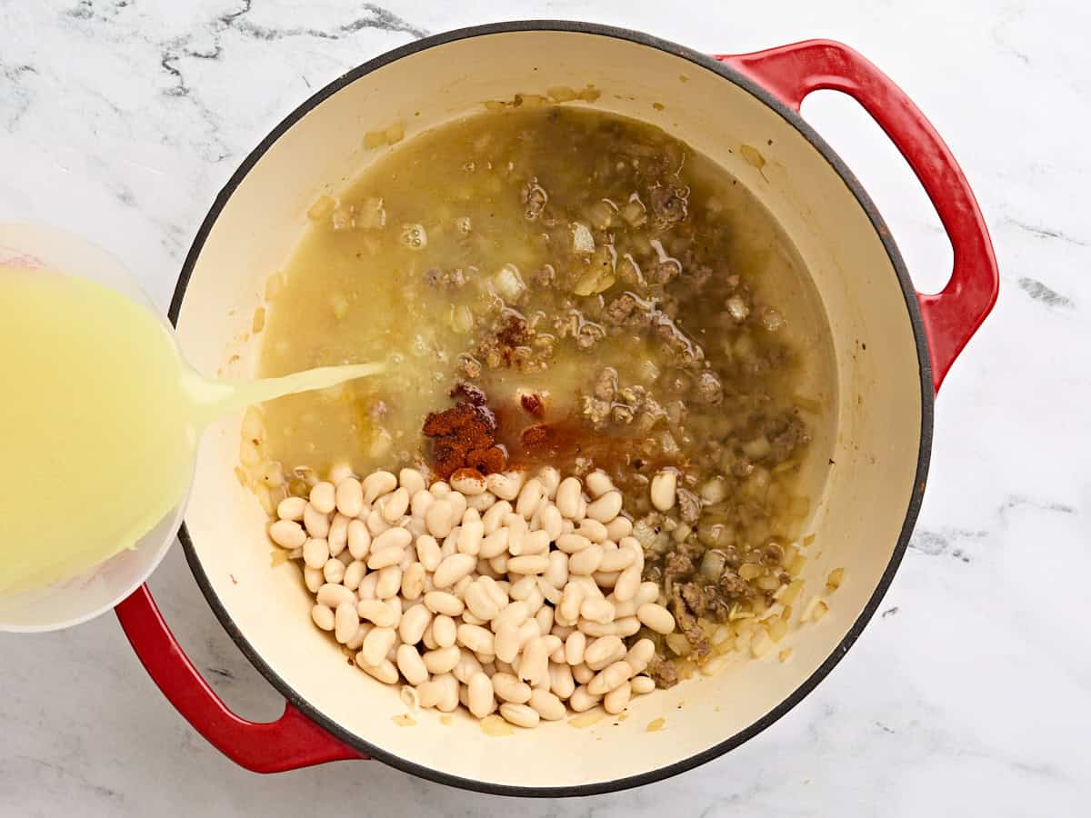 Great northern beans, smoked paprika and chicken broth added to a soup pot with sauteed ground sausage and onions.