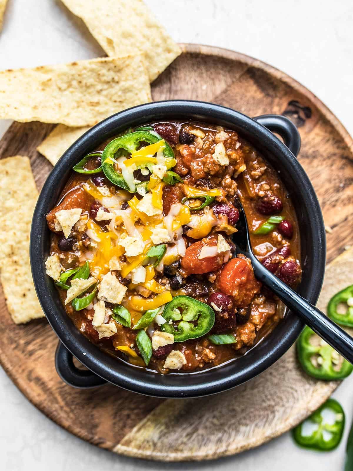 This no-frills basic chili recipe is ready for your personal touch. Learn how to make classic chili and what you can add to make it your own! Budgetbytes.com Overhead view of a bowl of beef chili with toppings and a spoon in the center.