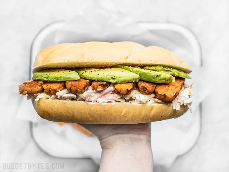 Spicy hot buffalo sauce, creamy avocado, and a rich and tangy ranch slaw makes these Buffalo Tempeh Sandwiches fiery perfection! Budgetbytes.com Buffalo Tempeh Sandwich in hand