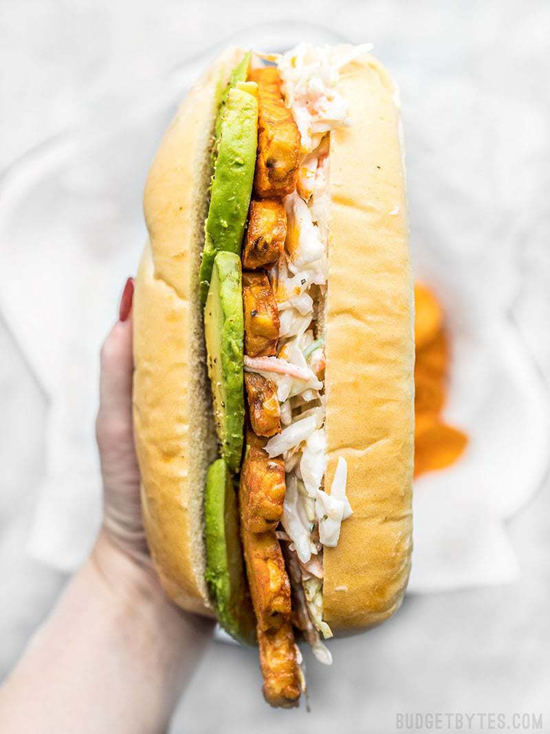 Spicy hot buffalo sauce, creamy avocado, and a rich and tangy ranch slaw makes these Buffalo Tempeh Sandwiches fiery perfection! Budgetbytes.com Close up of spicy hot Buffalo Tempeh Sandwiches