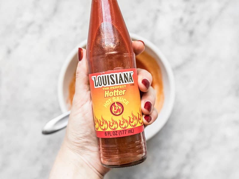 Louisiana Hot Sauce Louisiana Hot Sauce bottle being held over a bowl