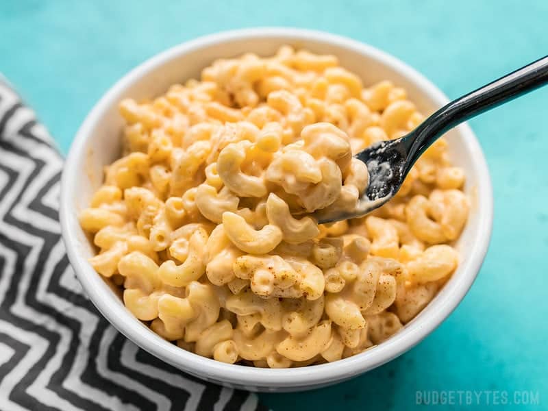 This rich and creamy Rice Cooker Mac and Cheese cooks up in just a few minutes and requires only a few simple ingredients. It’s the perfect fast fix! Budgetbytes.com Close up of a forkful of rich and creamy Rice Cooker Mac and Cheese