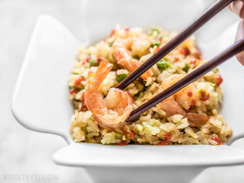 By adding a few extra ingredients to your rice cooker, you can cook an entire meal at once. This Teriyaki Shrimp and Rice is an easy and healthy alternative to take out. Budgetbytes.com Close up of chopsticks picking up a piece of shrimp out of the container of Teriyaki Shrimp and Rice