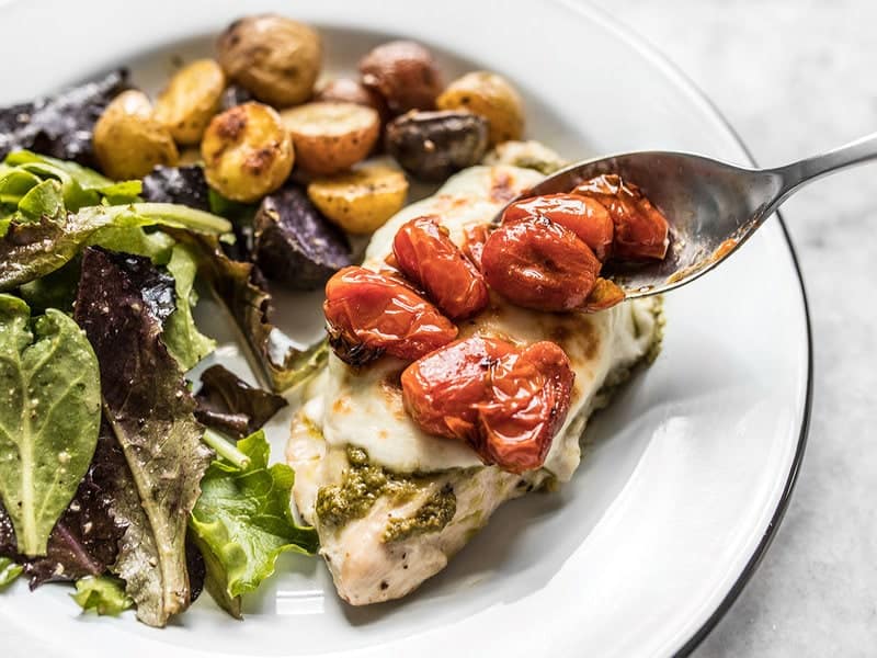 Sheet Pan Pesto Chicken Dinner is an easy to execute, simple yet elegant, and flavorful weeknight dinner that you’ll want to add to your weekly rotation! Budgetbytes.com Close up of roasted tomatoes on top of Sheet Pan Pesto Chicken DInner