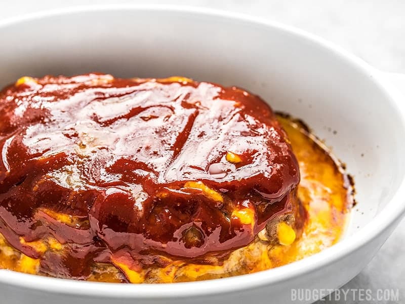 This super cheesy Cheddar Cheeseburger Meatloaf is studded with melty nuggets of cheddar, and topped with a tangy tomato-mustard sauce. Budgetbytes.com Cheddar Cheeseburger Meatloaf in a serving dish.