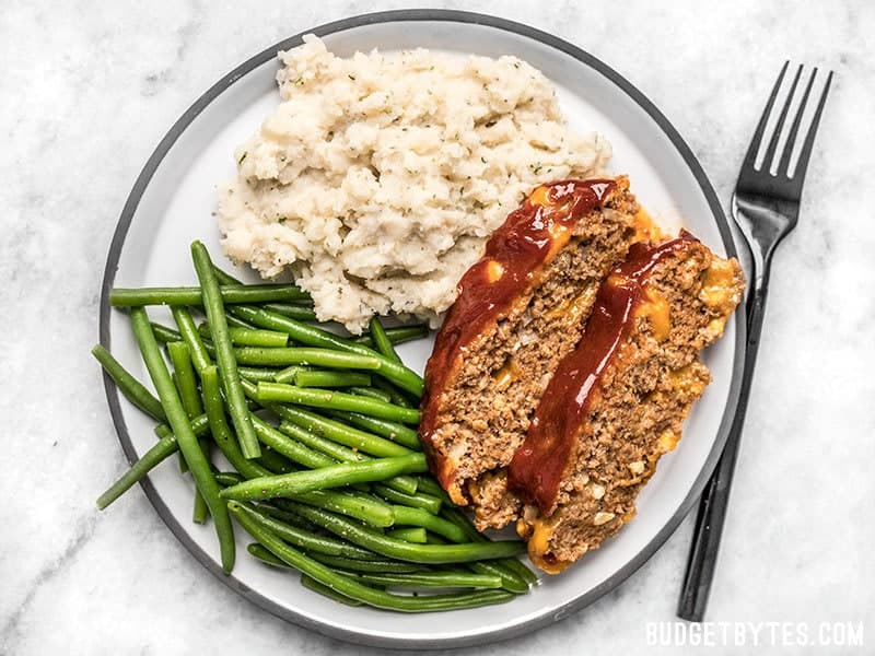 Fluffy as a cloud and with a rich buttery finish, these Garlic Herb Mashed Potatoes will be the star of any weeknight dinner or holiday meal! Budgetbytes.com Fluffy Garlic Herb Mashed Potatoes with green beans and Cheddar Cheeseburger Meatloaf