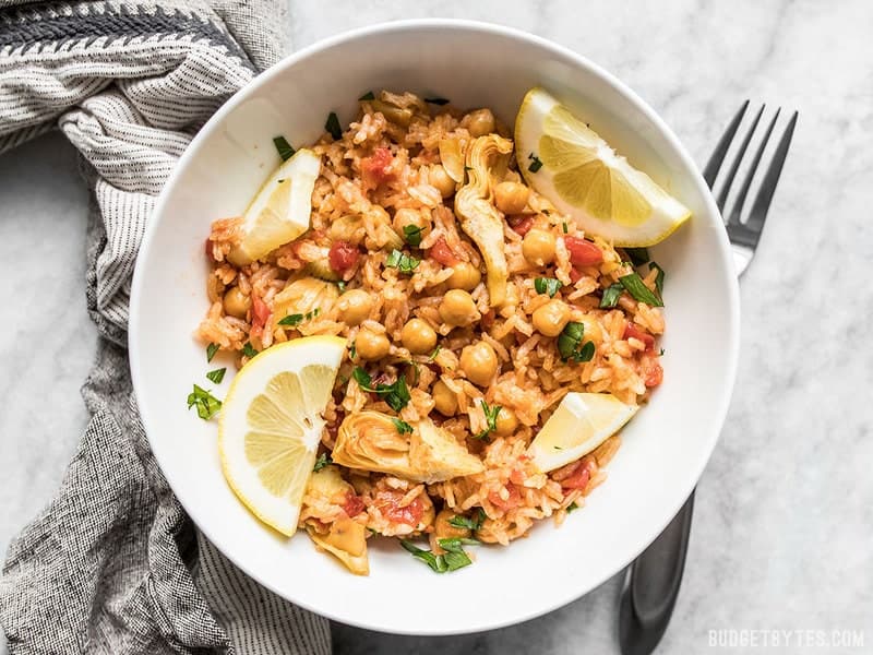 Rice Cooker Spanish Chickpeas and Rice is an incredibly easy and inexpensive vegan dinner that will keep you full and happy with very little effort. Budgetbytes.com A hearty bowl of Rice Cooker Spanish Chickpeas and Rice with fresh lemon and parsley