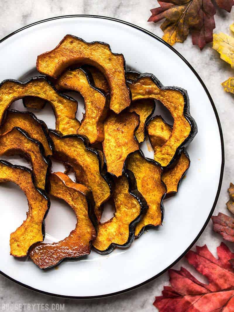 Smoky Maple Roasted Acorn Squash is an easy but elegant side dish that highlights fall produce. Easy enough for a week day, pretty enough for the holidays! Budgetbytes.com A plate full of Smoky Maple Roasted Acorn Squash on a holiday table.
