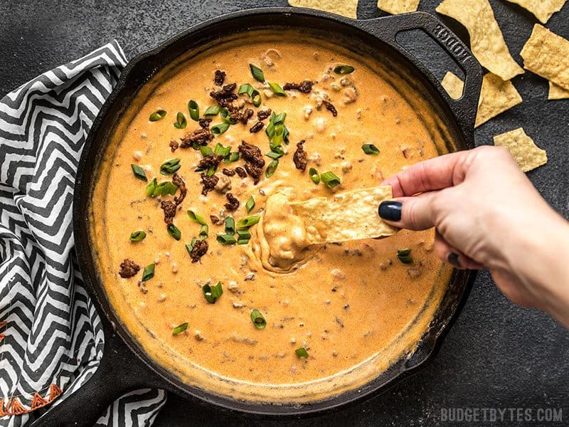 This incredibly easy Spicy Chorizo Cheese Dip only has five ingredients, no processed cheese, and is sure to be the star of your next party! Budgetbytes.com A chip being dipped into a skillet full of Spicy Chorizo Cheese Dip