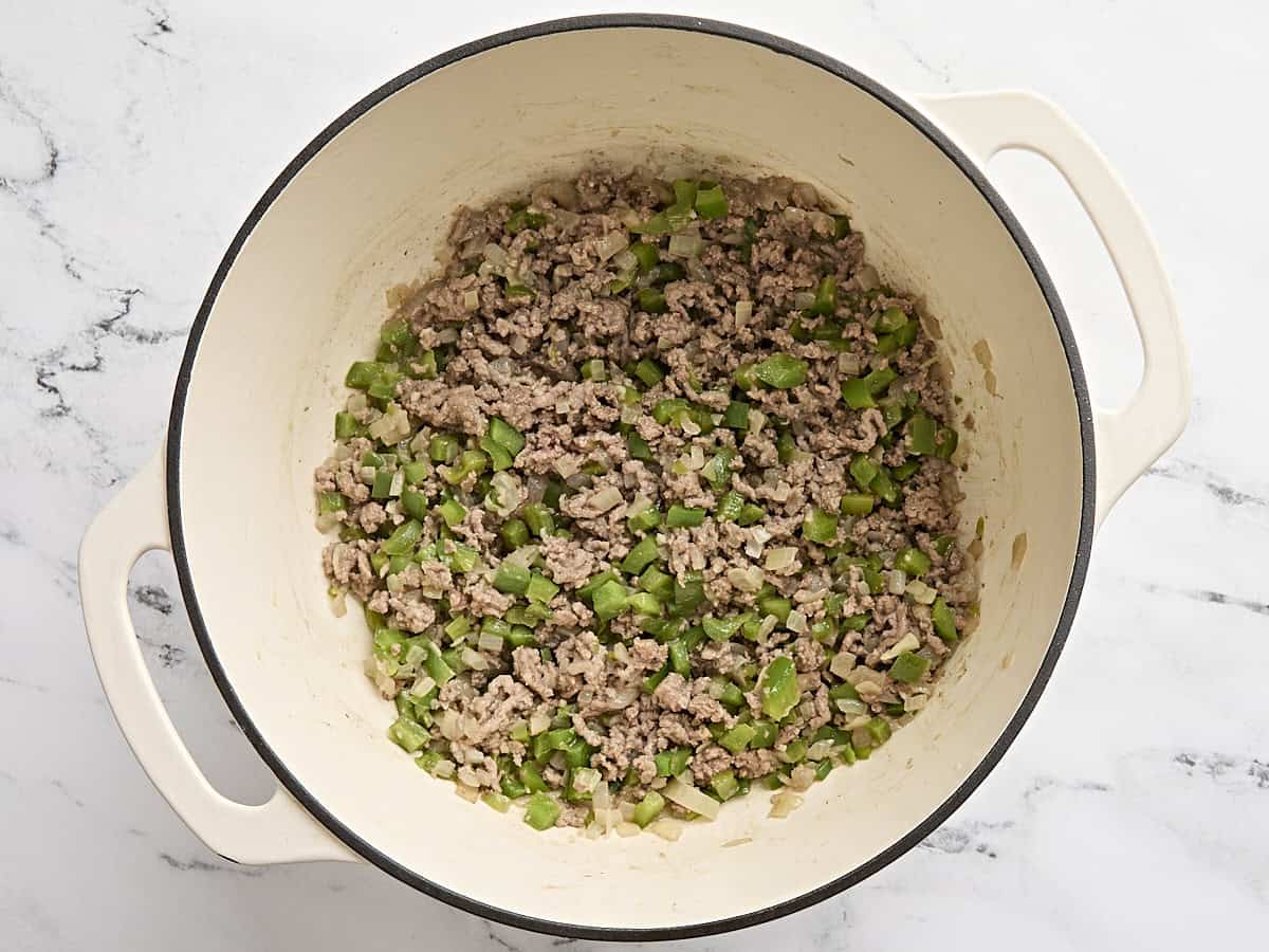 Ground beef added to sauteed veggies in a soup pot.