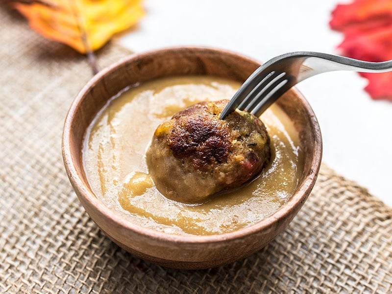 Turkey and Stuffing Meatballs make an easy and delicious addition to your Thanksgiving or Friendsgiving spread. Serve as an appetizer or main dish! Budgetbytes.com Turkey and Stuffing Meatballs being dipped into turkey gravy.
