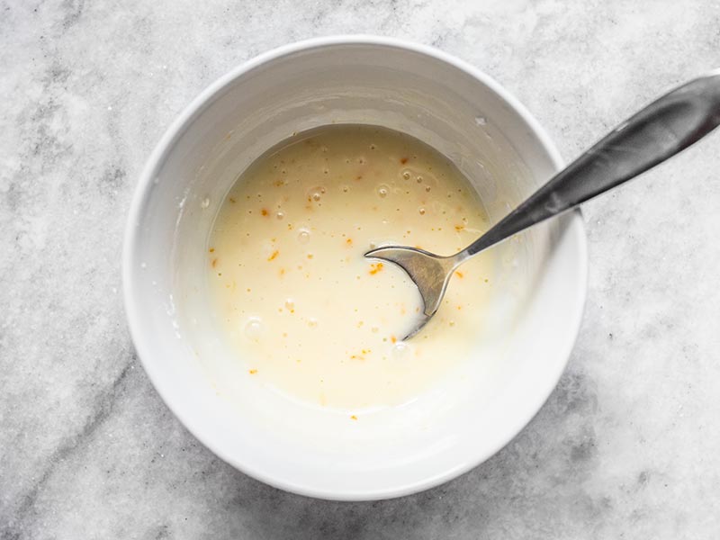 Orange glaze in a white bowl with a spoon.