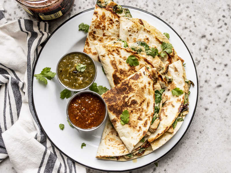 These Creamy Chicken and Spinach Quesadillas are seriously simple, but still deliciously dinner-worthy. Perfect for busy weeknights or picky eaters! Budgetbytes.com Creamy Chicken and Spinach Quesadillas on a plate with two types of salsa