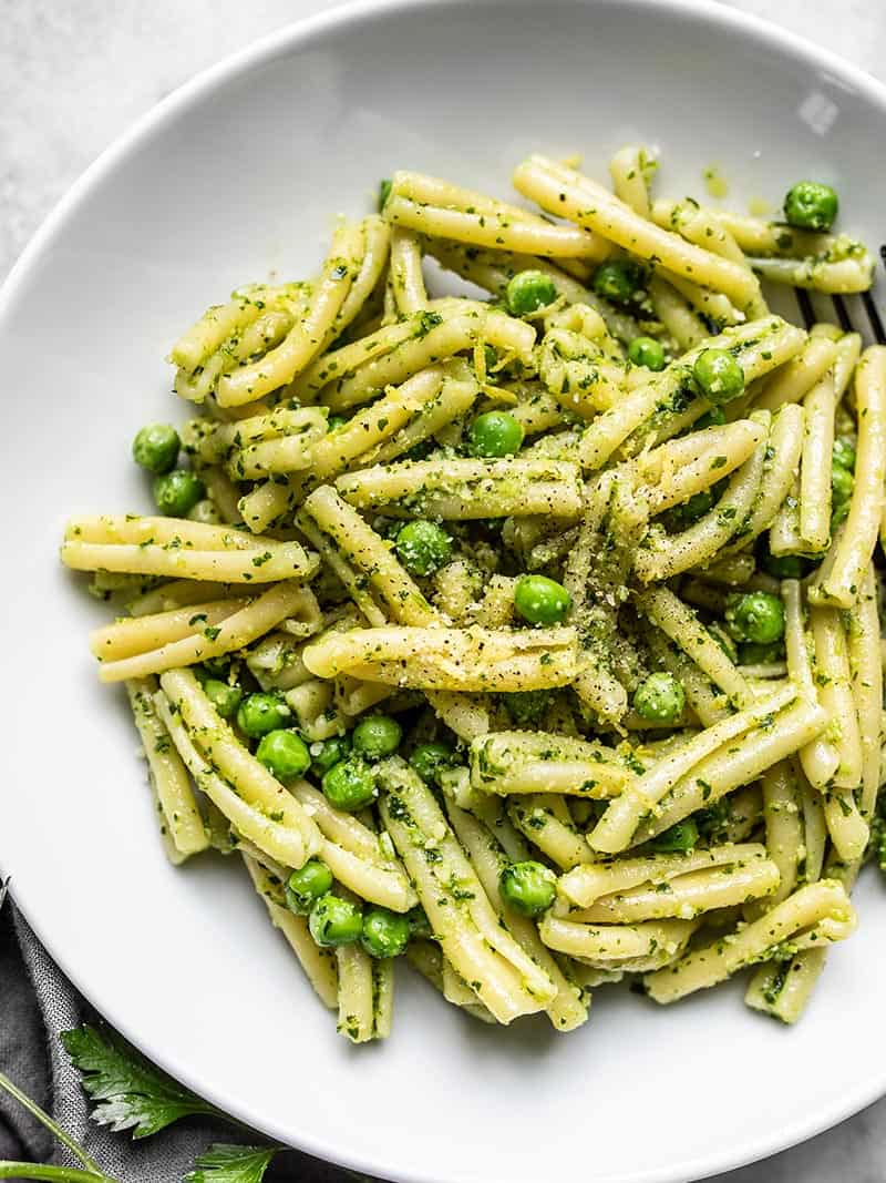 Parsley Pesto Pasta with Peas has super bright and fresh flavors perfect for spring and summer. Serve as a main dish or a side with your grilled food. Budgetbytes.com Close up of Parsley Pesto Pasta with Peas in a serving bowl