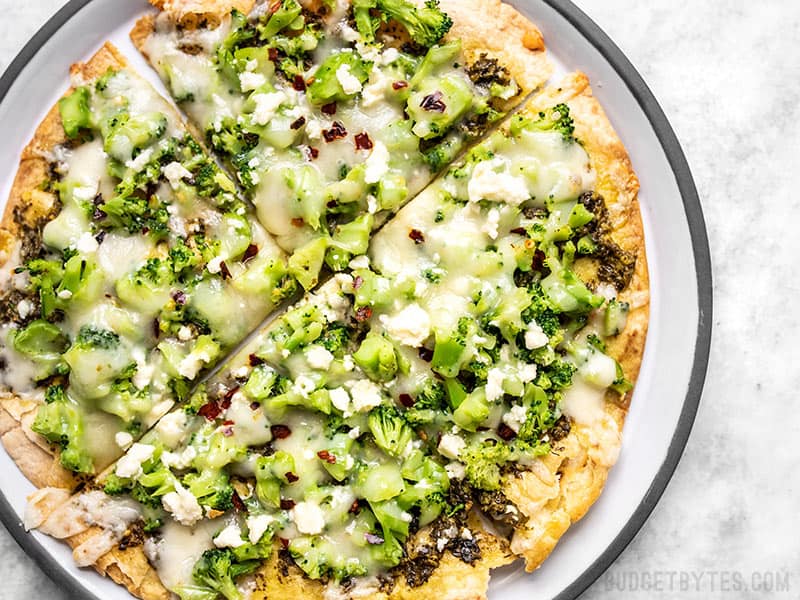 This "Quick Fix" Broccoli Pesto Pizza is the fastest and easiest route to getting your pizza fix, with an extra thin and crispy tortilla crust. Budgetbytes.com Close up of a Quick Fix Broccoli Pesto Pizza on a plate with crushed red pepper sprinkled on top.