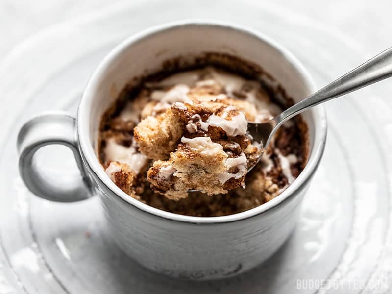 This Cinnamon Nut Swirl Mug Cake is the perfect way to get a single serving cinnamon roll fix without any kneading, rising, rolling, or baking! Budgetbytes.com A spoonful of a Cinnamon Nut Swirl Mug Cake being lifted out of the mug.