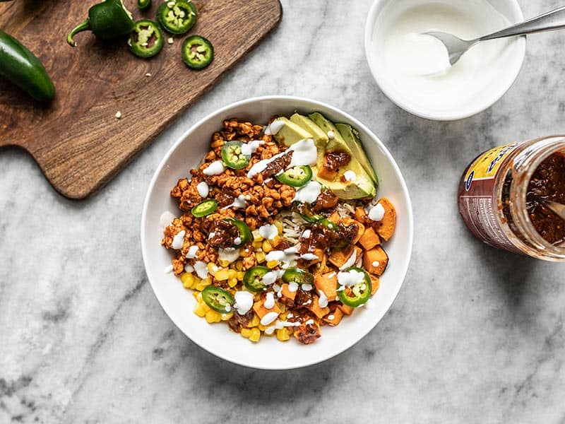 Spiced and crumbled tempeh makes a fast and easy alternative to beef in these Tempeh Burrito Bowls. Customize the toppings to be vegetarian or vegan! Budgetbytes.com Finished Tempeh Burrito Bowl, topped with sour cream.