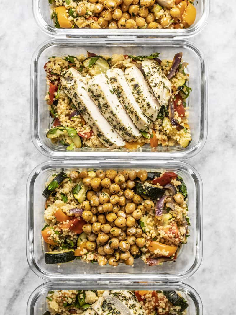 Roasted Vegetable Couscous Meal Prep is a super filling, veggie-packed meal that can be made with chicken or vegetarian with chickpeas. BudgetBytes.com Four glass meal prep containers lined up with Roasted Vegetable Couscous and Garlic Herb Baked Chicken or Garlic Herb Chickpeas