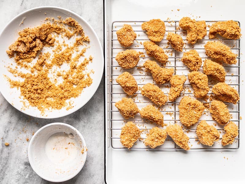 Chicken Nuggets Ready to Bake on wire cooling rack and baking sheet.
