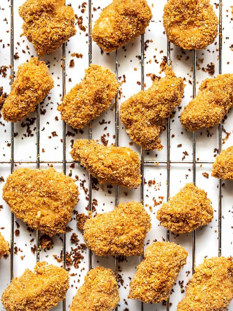 Homemade baked chicken nuggets are crispy on the outside, tender and juicy on the inside, easy to make, and make a delicious meal or snack. Budgetbytes.com Homemade Baked Chicken Nuggets on a wire cooling rack, close up.