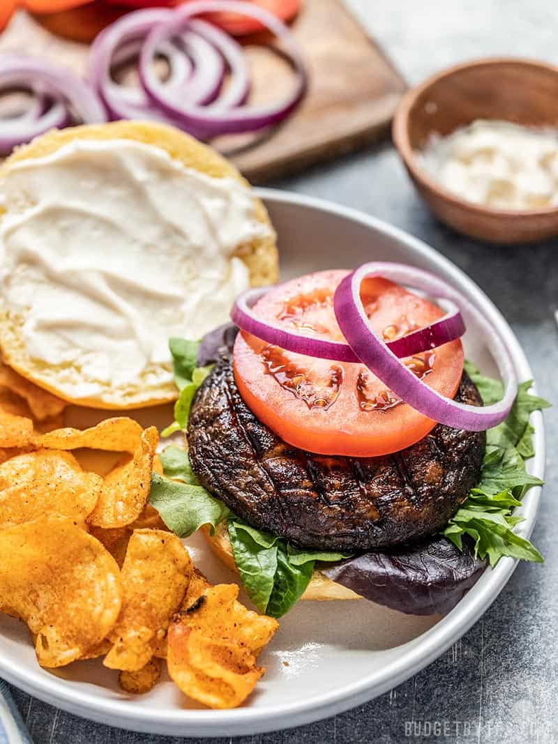 With their deep savory flavor, Marinated Portobello Mushroom Burgers are a fast and easy vegetarian option for summer grilling. Budgetbytes.com Marinated Portobello Mushroom Burger topped with tomato and onion on a plate with chips.