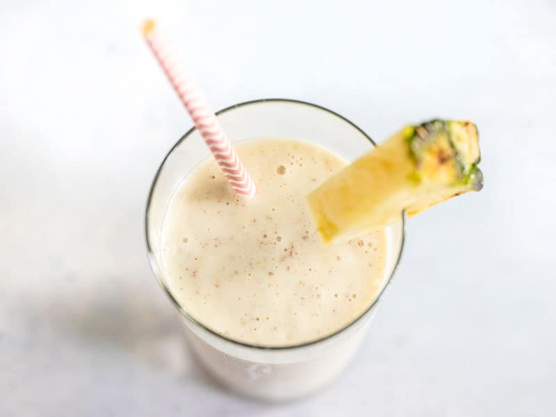 Cottage cheese is a surprisingly delicious and inexpensive source of protein in this sweet, tangy, and tropical Pineapple Protein Smoothie. Budgetbytes.com Close up of Pineapple Protein Smoothie in the glass, with a paper straw and fresh pineapple wedge on the rim.