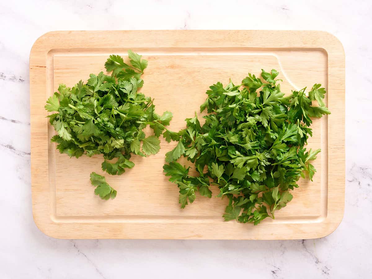 Cilantro and parsley on a cutting board.