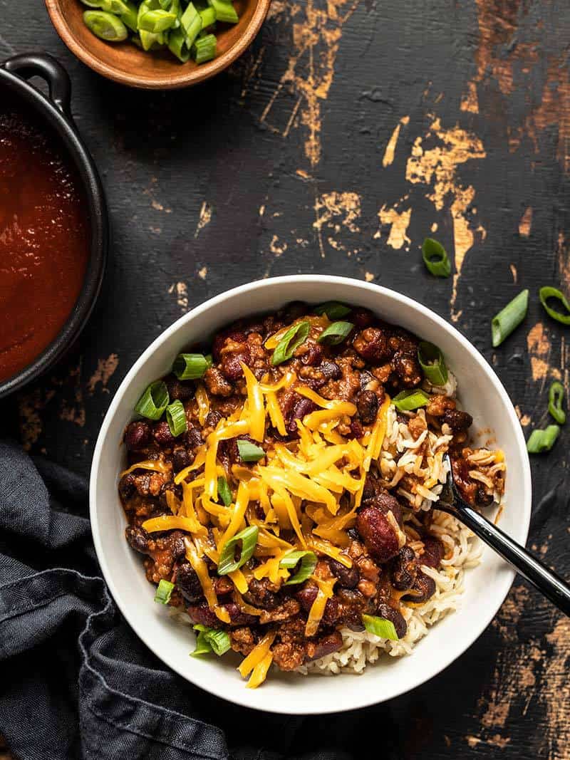 Serve these sweet, tangy, and savory BBQ Beef and Beans with rice and cheese for a simple and comforting weeknight dinner the whole family will love. Budgetbytes.com Finished bowl of BBQ Beef and Beans served over rice and topped with cheddar and green onions.