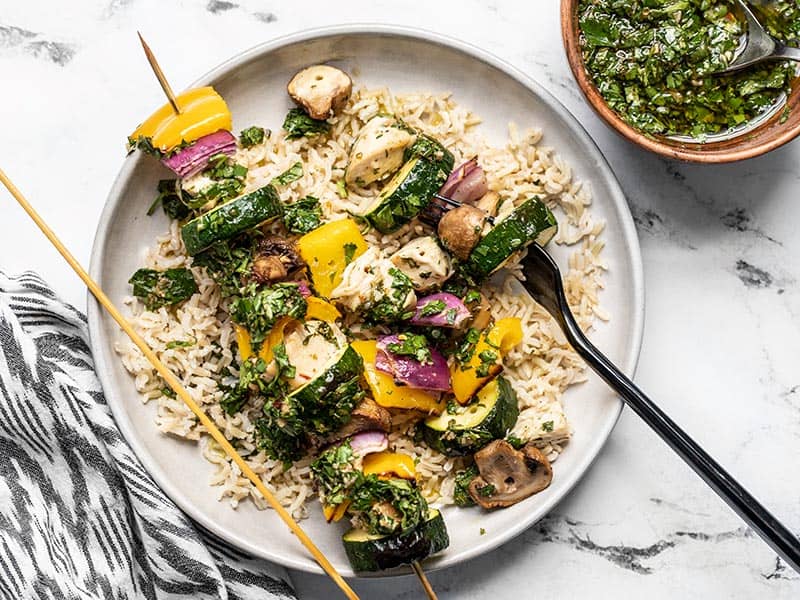 These Chimichurri Chicken Kebabs feature fresh vegetables and marinated chicken cooked over an open flame, then drizzled with a vibrant chimichurri sauce. Budgetbytes.com Chicken and vegetables removed from one skewer of a chimichurri chicken kebab, on a bed of rice.