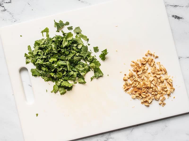 Chopped cilantro and peanuts on a cutting board.